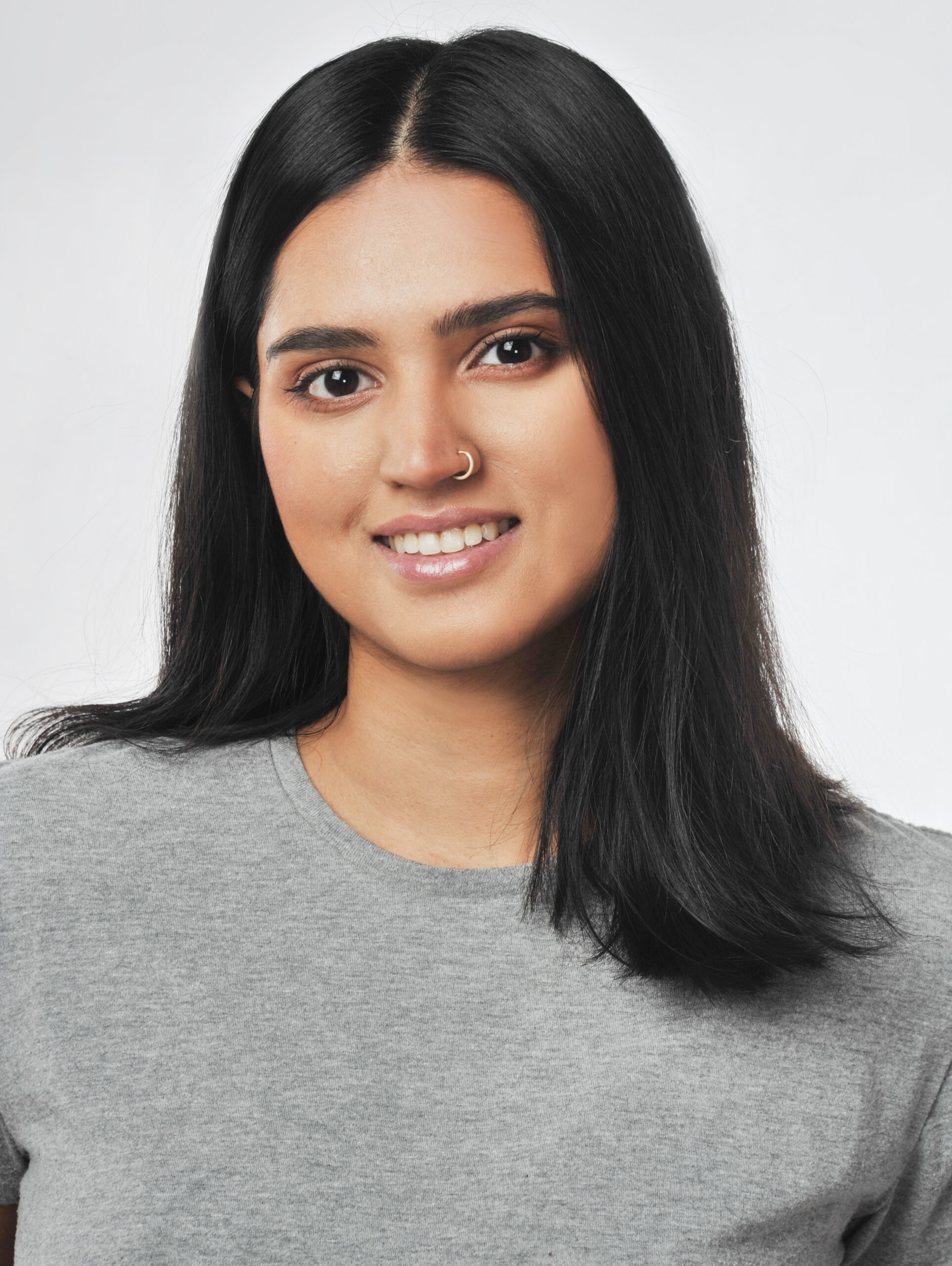 A photo of Purawai Vyas. She is a medium-light skinned woman with a nose ring, long dark hair and dark eyes. She's smiling at the camera.
