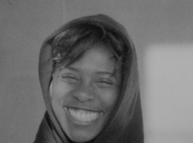 Headshot of Affiliate artist Aisha Sasha John smiling with head scarf